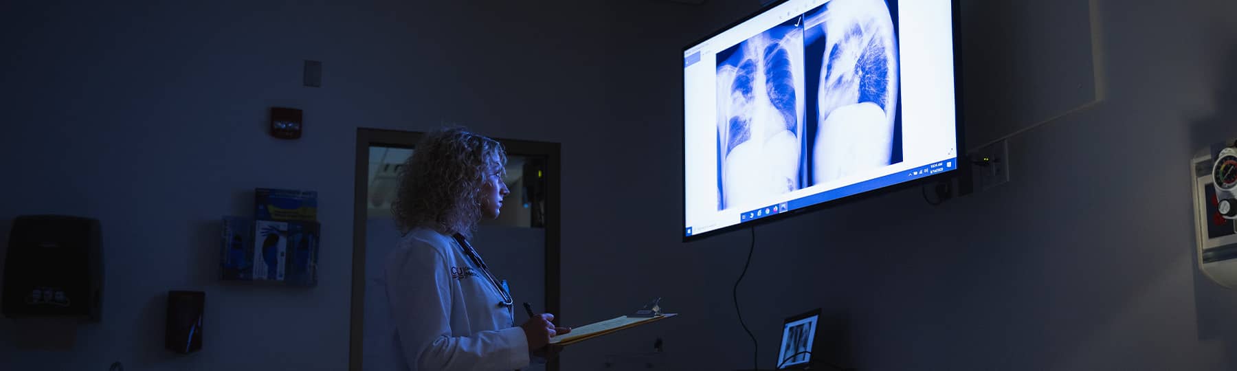 A CMU medical student in a dark room reading an x-ray off a screen. Taken from PhotoSource.