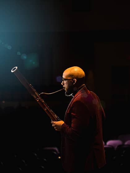 A CMU student in a red suit playing the bassoon during a concert. Taken from PhotoSource.