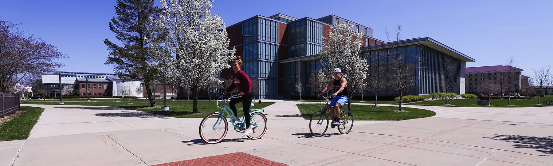 Bikers riding on campus, next to the College of Science and Engineering seal. Taken from PhotoSource.