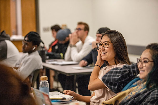 A group of male and female students sit in a classroom.