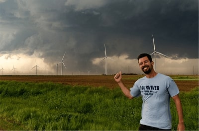 A person standing outside in the midst of a storm with a forming tornado.