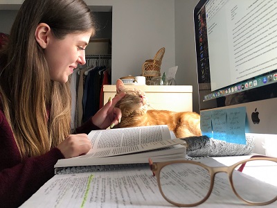 Emilee Madison working on a computer while petting her cat.