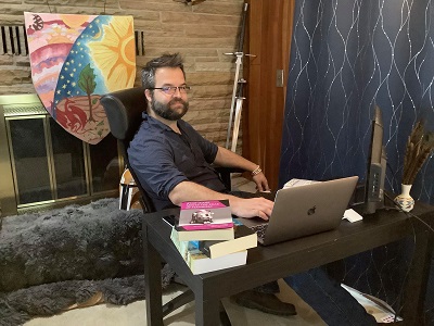 Evan Woolbright looking at the camera while sitting at a desk with books and a laptop.