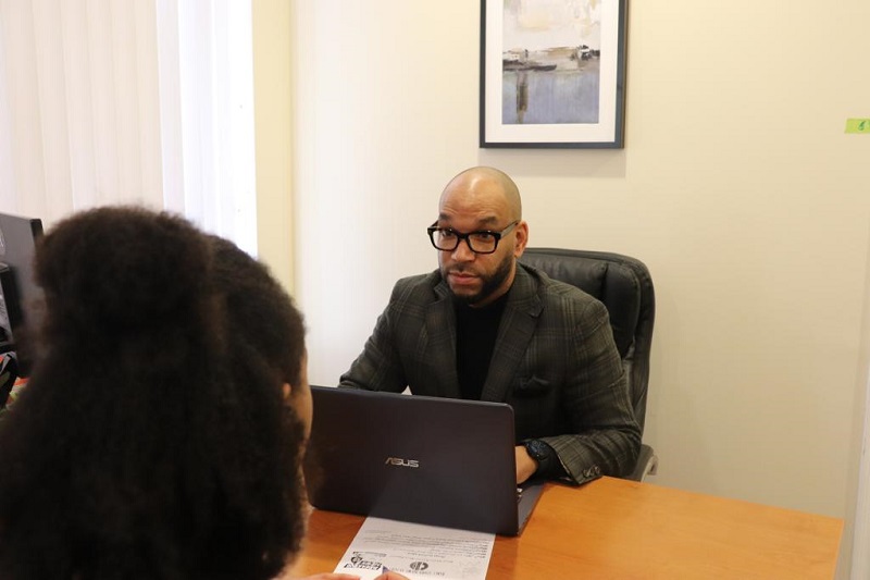 Jerome Cawley sitting at a table while working on a computer and wearing a suit.