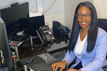 Lisa Hudson, an Educational Technology doctoral student, sitting at a desk in a blue blazer.