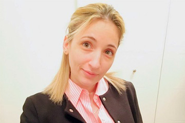 A woman in a pink collared shirt and blazer posing for a picture.