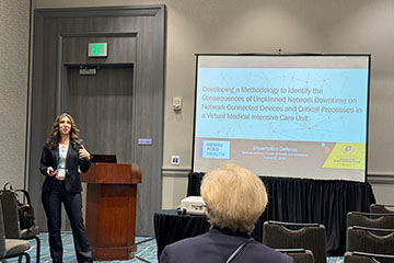 A woman presenting in front of a screen.