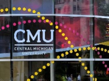 Central Michigan University logo displayed on a glass building facade with yellow and pink dotted design elements across the windows
