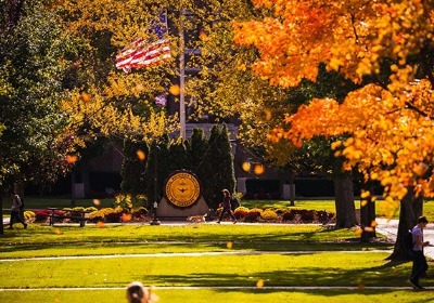 CMU seal and USA flag on campus with fall colors