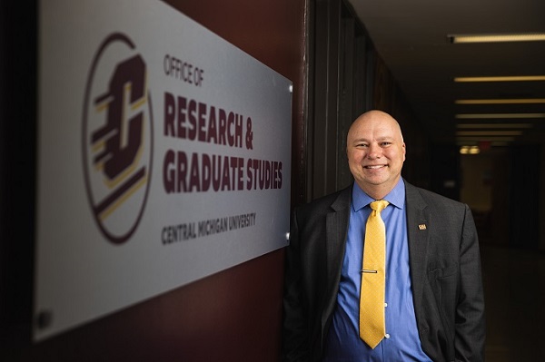 David Weindorf standing in a hallway by a Research and Graduate Studies sign.