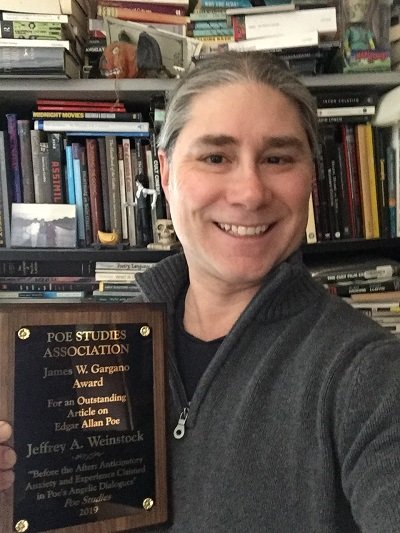 Professor Jeffrey Weinstock posing with his James W. Gargano Award from the Poe Studies Association.