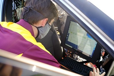 Dr. Jason Keeler sitting in a car and looking at information displayed on a computer.