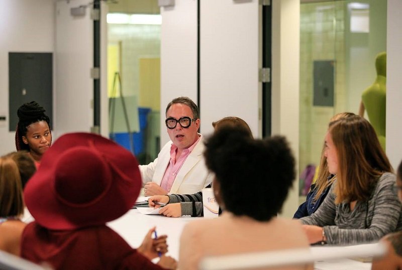 Dr. Michael Mamp sitting at a table and talking to students.