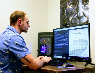 A person sitting at a computer developing a nuclear physics game.