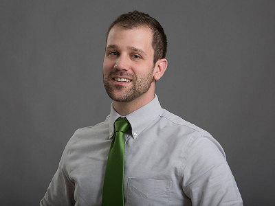 Professional headshot of Dr. James Gerhart in a button up shirt against a gray background.