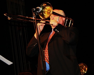 A person dressed in a suit playing the trombone.
