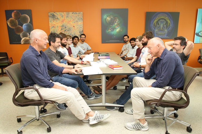 People involved with the Physics department sitting at a table while talking and looking at books.