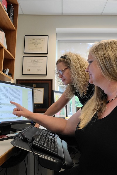 Two women looking at information on a computer with one of them pointing at the screen.