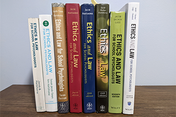 Eight books lined up on a table with their spines facing out.