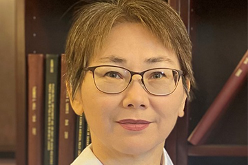 A woman in a white shirt standing in front of a bookcase.