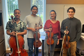 Four people posing for a picture with a cello, viola, and two violins.