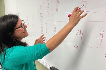 A woman writing on a whiteboard.