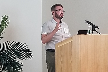A man in a collared shirt speaking from a podium.