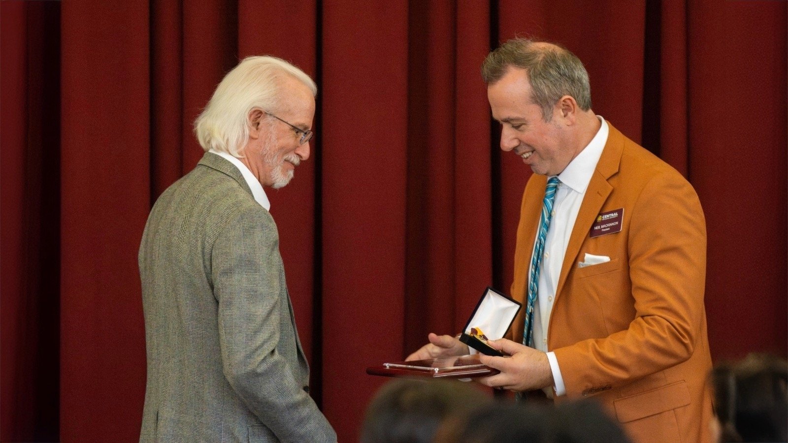 A man receiving an award from another man.