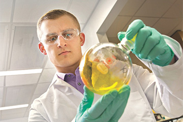 Biomedical student holding a beeker in the lab.