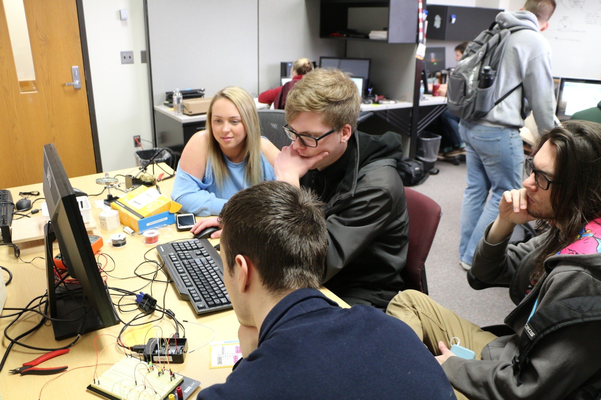 Students sit around a computer in the SAP Lab in the College of Business Administration at Central Michigan University.
