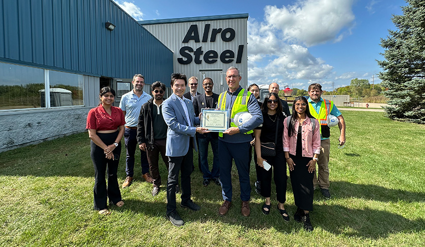 Alpha Iota Delta students, faculty and Alro Steel employees gather outside the company’s Clare facility during a factory tour.