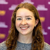 Holly Ireton smiling in a professional headshot, with a blurred maroon CMU backdrop.