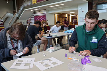 High school students work together in groups on camp projects in the Grawn Atrium
