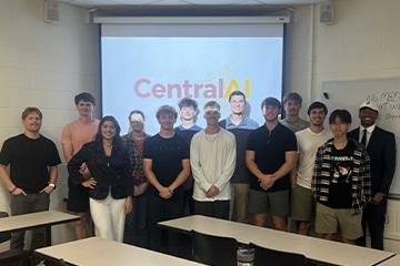 Thirteen business students stand in front of a projector screen that shows the Central AI logo. They are gathered for a regular RSO meeting on campus where they talk about AI in business.