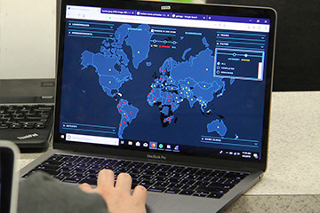 Cybersecurity student exploring a world map on their laptop while playing capture the flag.