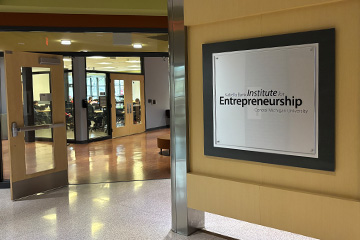 Entrance to the Isabella Bank Institute for Entrepreneurship at Central Michigan University, featuring the institute sign and open doors to collaborative workspace areas.