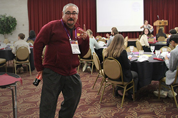 Nick Hussein wears a maroon sweater and dark grey pants as he poses and flashes a peace sign in the UC Rotunda.