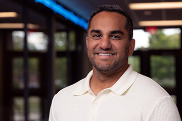 CMU management faculty member Tomas Thundiyil smiles for a portrait inside Grawn Hall.