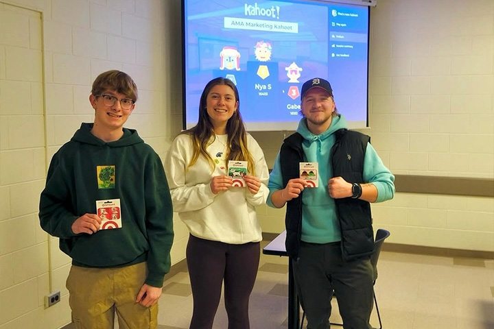 Three CMU students pose with gift cards after winning an American Marketing Association trivia activity.