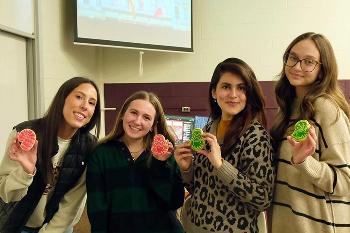 Four CMU students hold decorated cookies during an American Marketing Association social event.
