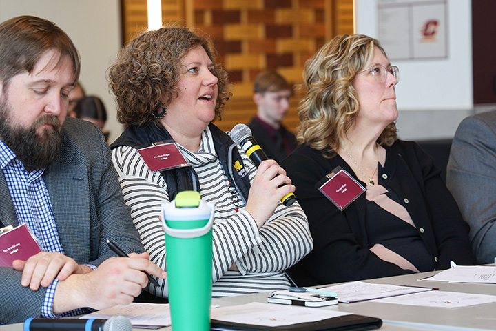 Boss Games judges listen and take notes as one speaks into a microphone during a student competition event.