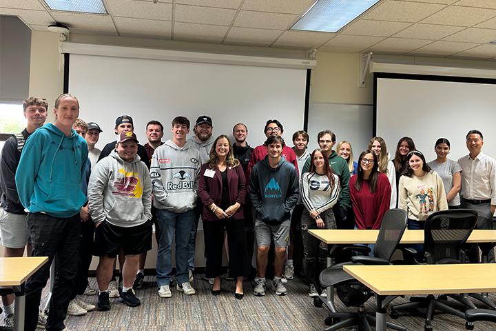 Kristin Schooley poses with students and a faculty member in a CMU classroom during Dialogue Days.