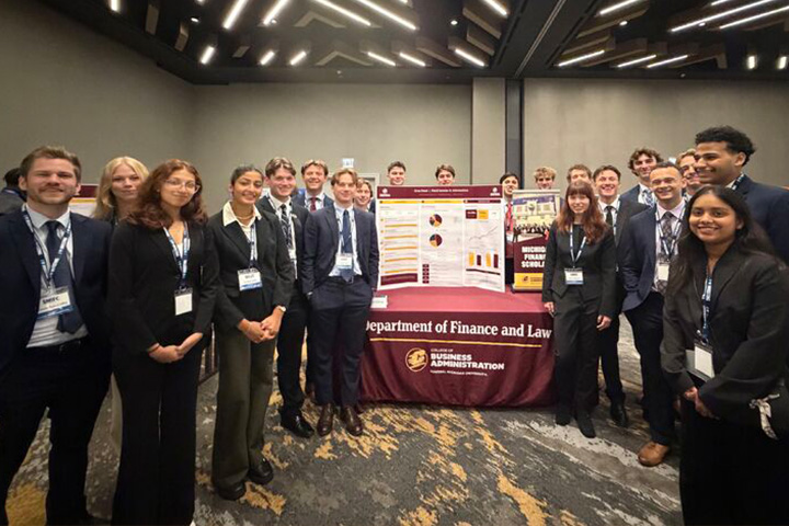 CMU finance students and faculty pose around their Oros Fund investment poster at the Student Managed Investment Fund Conference in Chicago.