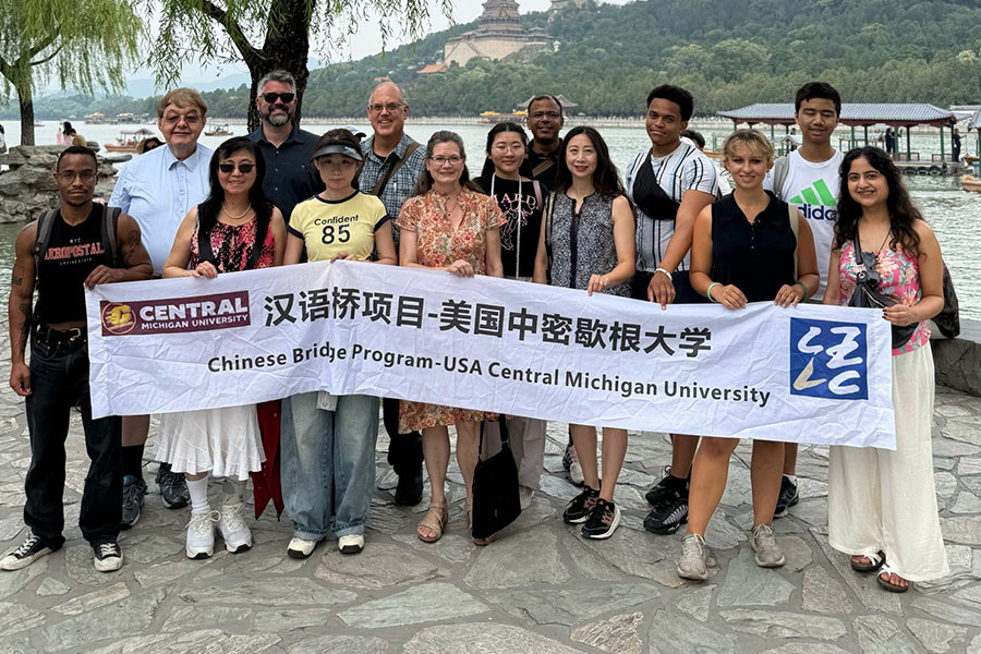 900x600_Article_Inset_China_Trip Students and faculty rom the CBA stand with Chinese counterparts from the Zhejiang University of Technology. They hold a banner tin Chinese and English that reads Chinese Bridge Program-USA Central Michigan University. Behind them is a river and temple.
