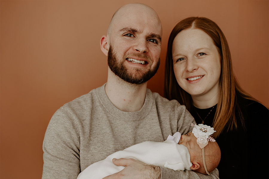 Brandon Diebolt stands next to his wife and holds his newborn baby Scarlett.