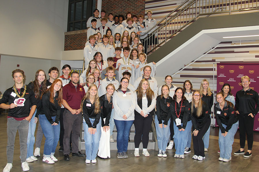 GI-TEC high school students, CBA student mentors and faculty members crowd the Grawn Atrium staircase from top to bottom. The high schoolers wear gray next-gen branded shirts on the stairs, the mentors in black shirts pose at the bottom of the stairs.