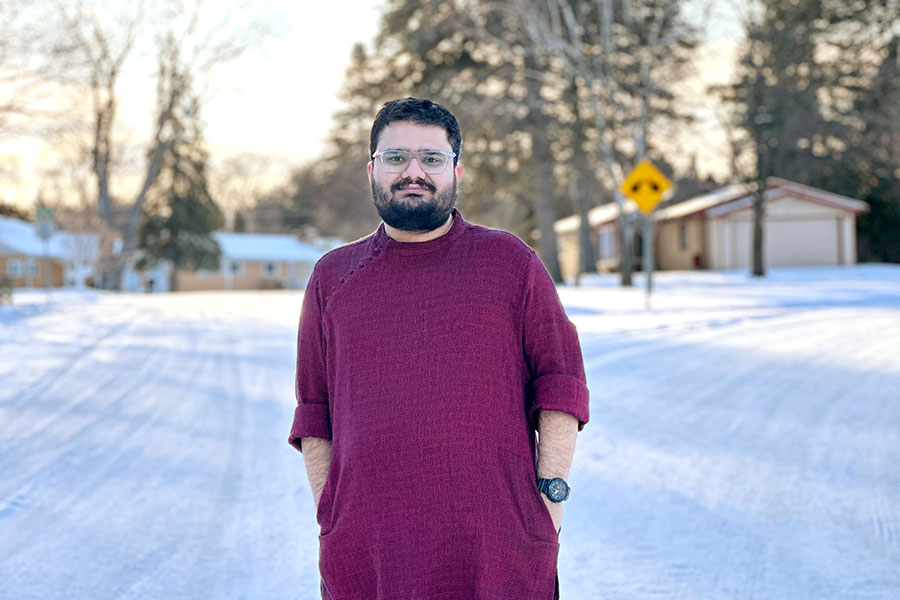 900x600_Article_Inset_PhaniNanduri1 Phani Anudeep Nanduri stands outdoors in winter with snow on the ground. He's wearing a maroon short sleeve shirt, jeans, and a pair of black shoes. He has short dark, curly hair, a short beard and glasses.
