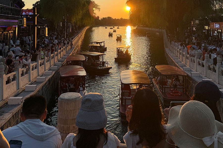 900x600_Article_Inset_River People crowd railings around a Chinese river. They are attempting to capture the sunset and many boats that are on the river.
