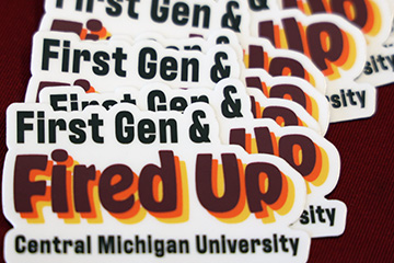 Close up of Fired Up First Gen stickers on a maroon table.