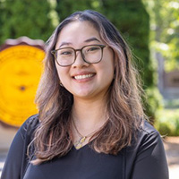 Lindsey Nguyen smiling in a professional headshot, wearing glasses outdoors with the CMU seal in the background.